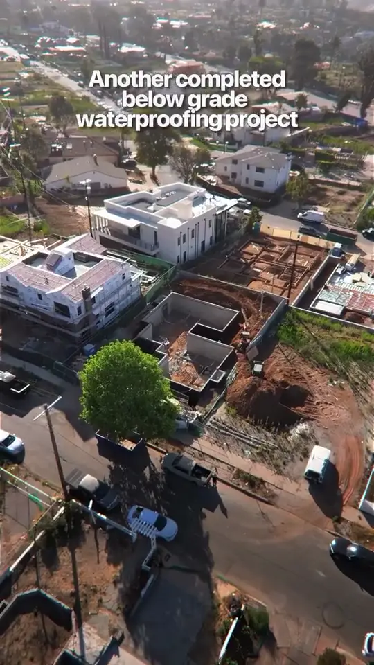Below-grade complete — A hillside foundation sealed before the dirt goes back.