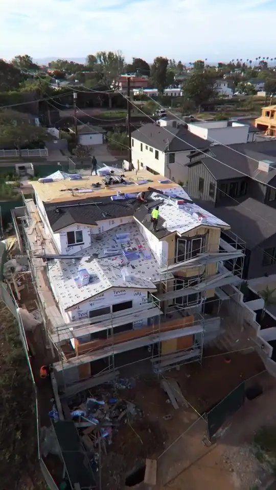 Re-roof in progress — Underlayment down, crew on the deck, scaffolding wrapped.